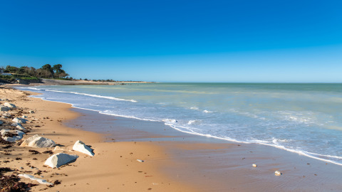 Zandstrand en rustige zee bij Flower Camping Monplaisir in Nouvelle-Aquitaine, Frankrijk, op een zonnige dag.