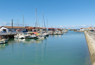 Boten aangemeerd in de haven met rode daken bij Flower Camping Monplaisir, Nouvelle-Aquitaine, Frankrijk.