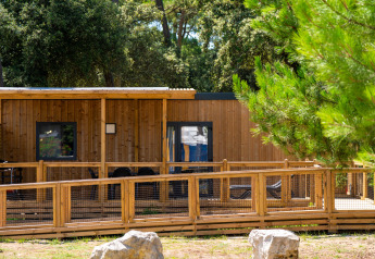 Vista de la cabaña Premium Stacaravan PRM con dos dormitorios, terraza de madera y entorno natural.