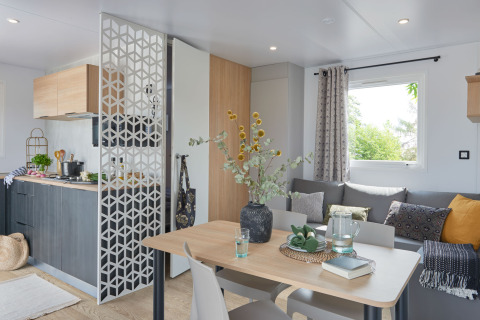 Moderno salón y cocina en una Premium Stacaravan en Flower Camping Monplaisir, Francia, con decoración acogedora.