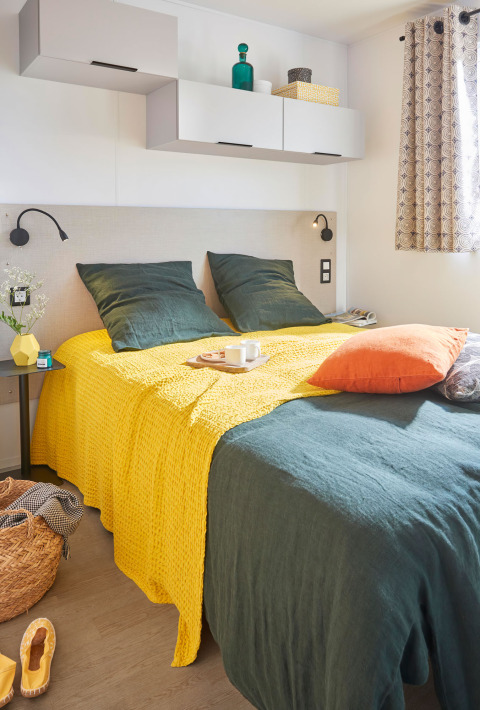 Komfortabelt soveværelse i Premium Stacaravan med gul og grøn indretning på Flower Camping Monplaisir i Frankrig.