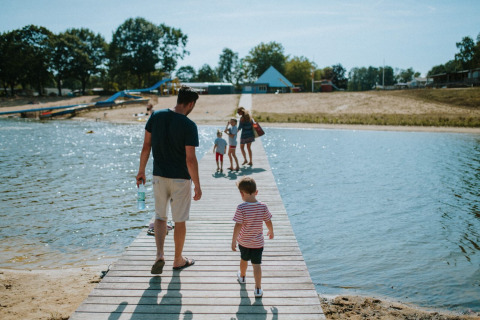 Gezin wandelt op houten steiger over het water in Wilsumer Berge, een vakantiepark in Nedersaksen, Duitsland.