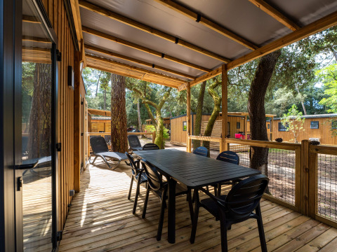 Überdachte Holzterrasse mit Esstisch, Stühlen und Liegen im Premium Stacaravan, Camping Monplaisir.