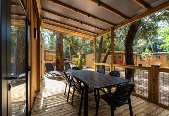 Covered wooden deck with dining table, chairs, and loungers at Premium Stacaravan, Flower Camping Monplaisir.