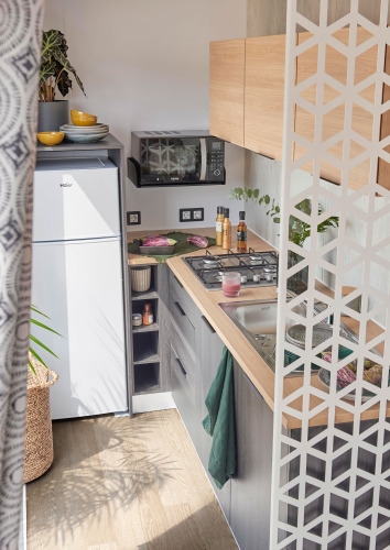 Cucina compatta moderna in cabina con mobili in legno, fornello, lavello, microonde e frigo Haier.