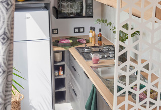 Cucina compatta moderna in cabina con mobili in legno, fornello, lavello, microonde e frigo Haier.