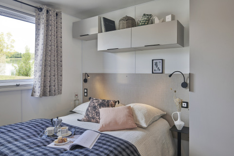 Camera moderna nella Premium Stacaravan al Flower Camping Monplaisir, con letto, armadietti e finestra.