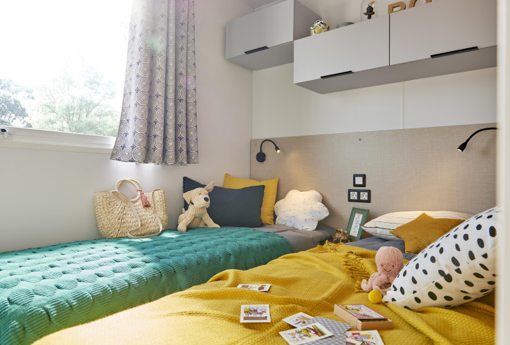 Chambre d’enfant lumineuse et chaleureuse dans une Premium Stacaravan avec coussins et jouets au Flower Camping Monplaisir.