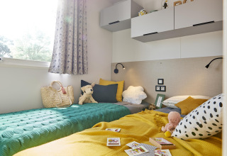 Luminescente e accogliente cameretta nella Premium Stacaravan con cuscini colorati e giocattoli a Flower Camping Monplaisir.