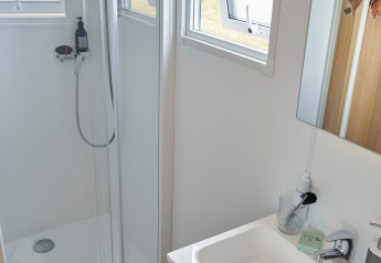 Bagno moderno nella Premium Stacaravan con doccia, lavabo, specchio e finestre aperte al Flower Camping Monplaisir.