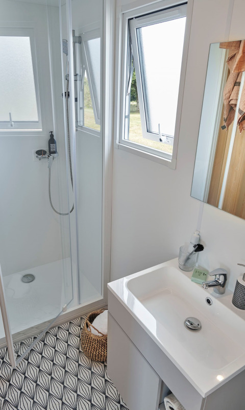 Bagno moderno nella Premium Stacaravan con doccia, lavabo, specchio e finestre aperte al Flower Camping Monplaisir.