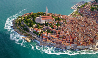 Luftfoto af historisk by ved Adriaterhavet nær Pomer, Istrien, Kroatien, med kirketårn og kystlinje.