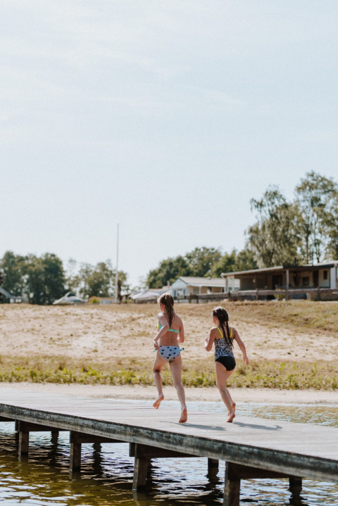 Twee kinderen rennen op een steiger bij het water in het vakantiepark Wilsumer Berge, Duitsland.