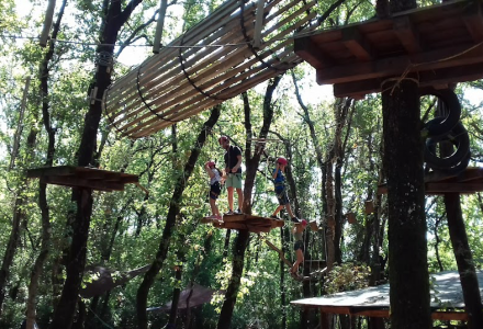 Folk deltager i et eventyrpark reb-bane i skoven nær Pomer, Istrien, Kroatien, omgivet af træer.