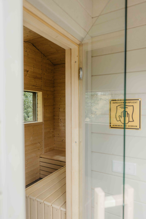 Entrada a una sauna moderna de madera vista desde la puerta de una tiny house en Wilsumer Berge, Alemania.