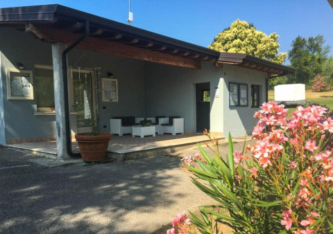 Eingang des Sivinos Camping Boutique in der Lombardei, Italien, mit Blumen und Sitzbereich im Freien.