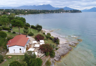 Aerial view of Sivinos Camping Boutique by Lake Garda in Lombardy, Italy, showing shoreline and mountains.