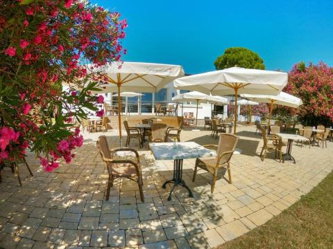 Udendørs terrasse på Sivinos Camping Boutique i Lombardiet, Italien, med parasoller og blomstrende buske.