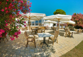 Udendørs terrasse på Sivinos Camping Boutique i Lombardiet, Italien, med parasoller og blomstrende buske.