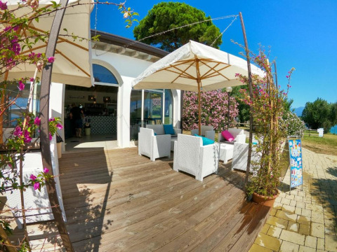 Außenterrasse mit weißen Möbeln und Sonnenschirmen im Sivinos Camping Boutique, Lombardei, Italien.