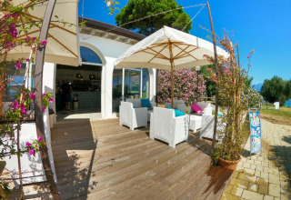 Buitenterras met witte zetels en parasols bij Sivinos Camping Boutique in Lombardije, Italië.
