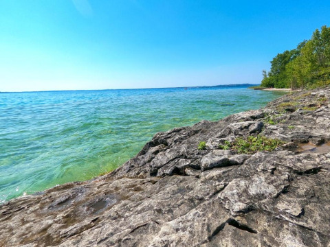 Rocky shoreline and clear blue water at Lake Garda near Manerba del Garda, Lombardy, Italy, on a sunny day.