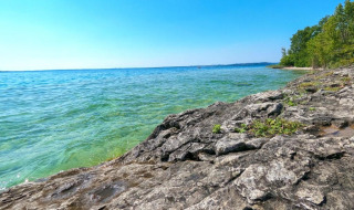 Riva rocciosa e acqua limpida sul Lago di Garda vicino a Manerba del Garda, Lombardia, Italia, in una giornata serena.