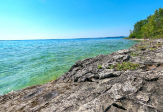 Rocky shoreline and clear blue water at Lake Garda near Manerba del Garda, Lombardy, Italy, on a sunny day.