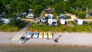 Vista aerea dei camper sulla spiaggia di Sivinos Camping Boutique, Lombardia, Italia, immersi nel verde.