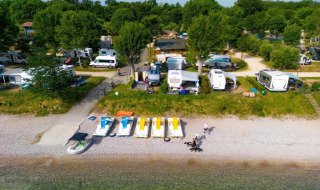 Vista aerea dei camper sulla spiaggia di Sivinos Camping Boutique, Lombardia, Italia, immersi nel verde.