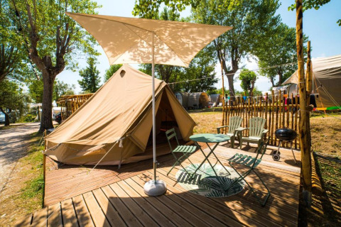 Outdoor glamping tent with deck, chairs, and sunshade at Sivinos Camping Boutique in Lombardy, Italy.