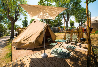 Tienda de glamping con terraza, sillas y sombrilla en Sivinos Camping Boutique en Lombardía, Italia.