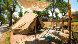 Tenda glamping con veranda, sedie e parasole al Sivinos Camping Boutique in Lombardia, Italia.