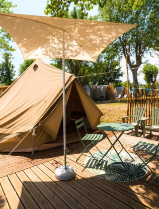 Tenda glamping con veranda, sedie e parasole al Sivinos Camping Boutique in Lombardia, Italia.