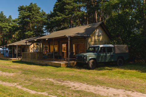 Glamping tent met terras en Land Rover Defender geparkeerd bij het Wilsumer Berge vakantiepark in Duitsland.