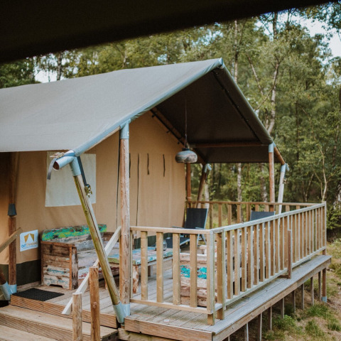 Glamping tent met houten terras en zitmeubilair bij Wilsumer Berge vakantiepark in Nedersaksen, Duitsland.