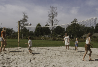 Familia juega voleibol en la arena junto a una tiny house en Camping Si-Es-An, Países Bajos.