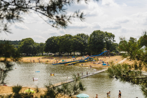 Mensen genieten van het strand en het water met een glijbaan bij vakantiepark Wilsumer Berge, Duitsland.