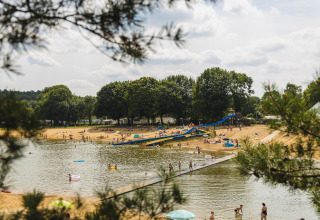 Mensen genieten van het strand en het water met een glijbaan bij vakantiepark Wilsumer Berge, Duitsland.