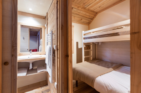 Vue intérieure du Chalet Montana Vista aux Chalets Huttopia Champagny en Vanoise avec lits superposés et salle de bain.