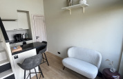 Petit salon moderne avec canapé, chaises hautes et kitchenette au Holiday Park Eigen Wijze, Pays-Bas.