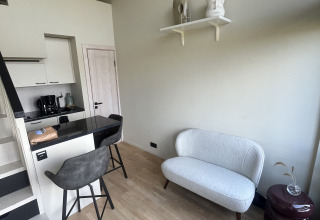 Moderne lille stue med sofa, barstole og køkken i Tiny house på Holiday park Eigen Wijze, Holland.
