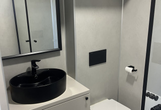 Moderne badeværelse i et tiny house ved Holiday park Eigen Wijze, Holland, med sort vask og toilet.