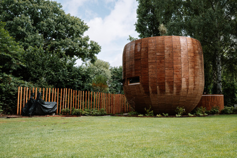 Rond houten tiny house met hek en gazon in Recreation Park Den Blanken, Nederland.