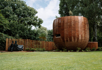Pequeña casa redonda de madera con cerca en un parque verde en Recreation Park Den Blanken, Países Bajos.