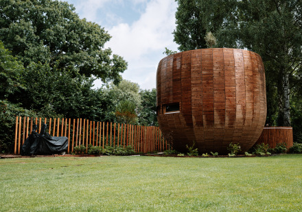 Rond houten tiny house genaamd The Nutshell met hekwerk en tuin bij Recreation Park Den Blanken.