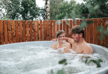 Paar entspannt sich mit einem Glas Wein im Whirlpool bei The Nutshell, Recreation Park Den Blanken, Niederlande.