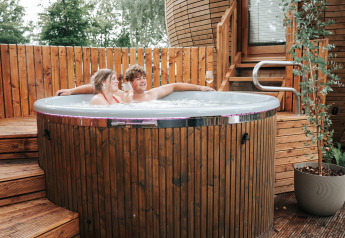 Koppel ontspant in een hot tub bij The Nutshell tiny house met sauna op Recreation Park Den Blanken.