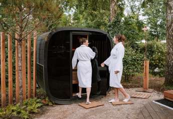 Due persone in accappatoio entrano in una sauna esterna a The Nutshell al parco Den Blanken nei Paesi Bassi.