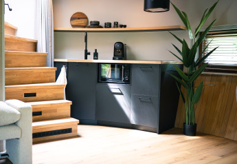 Moderne kitchenette, houten trap, grote plant en lichtinval in tiny house The Nutshell te Den Blanken.